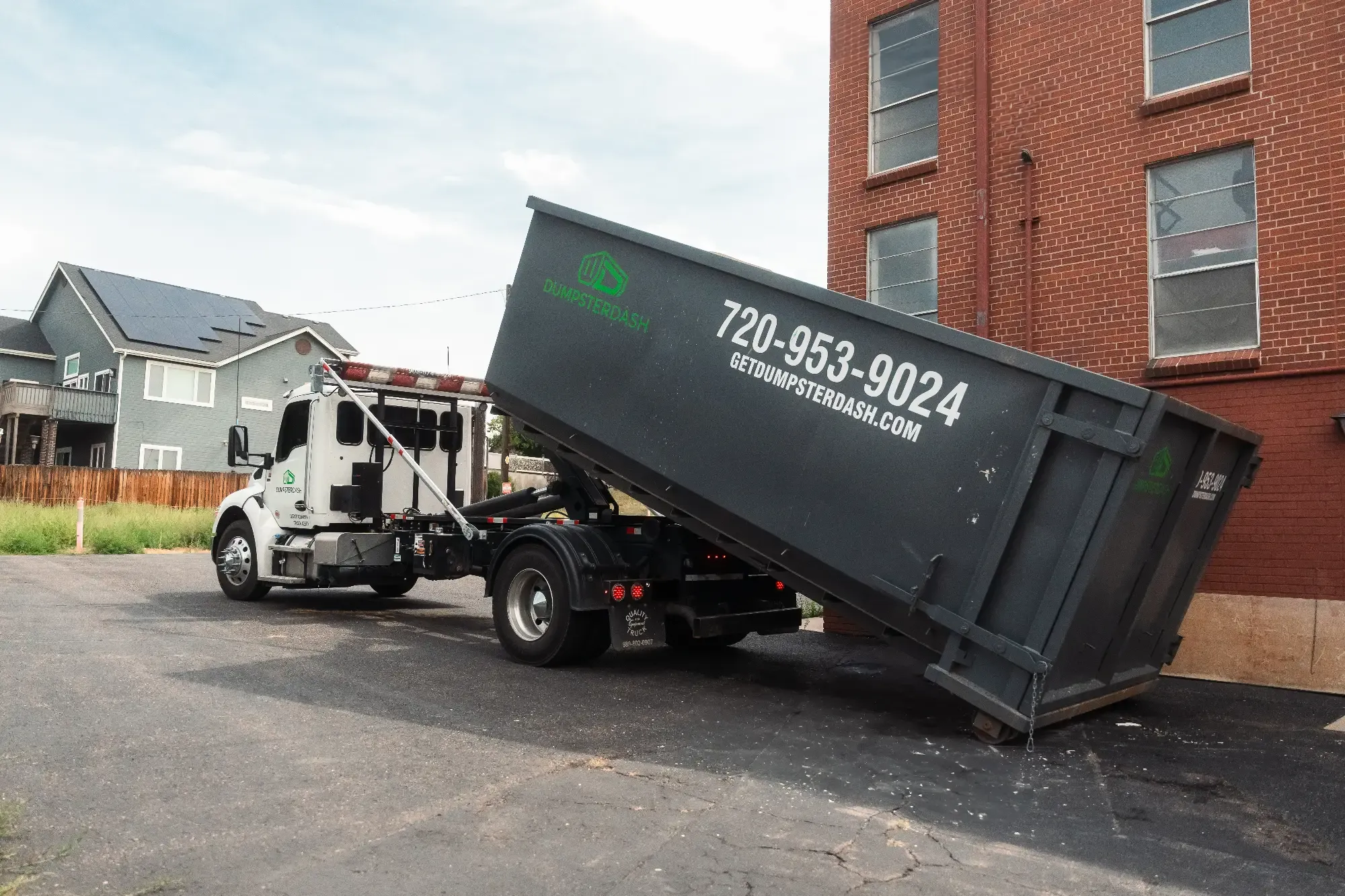 DumpsterDash truck unloading a roll-off dumpster